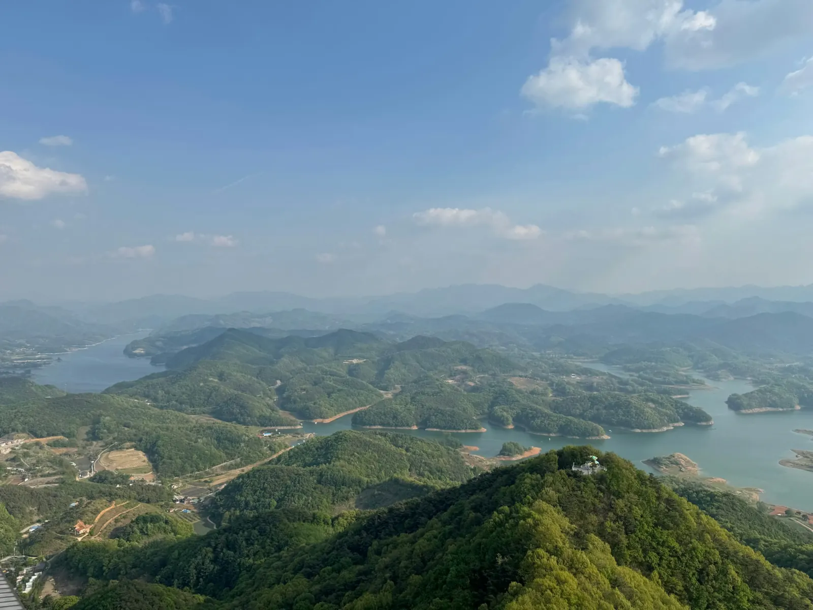 초록 산에 둘러싸인 넓은 호수 항공 사진